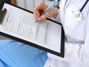 Woman doctor at work at hospital. Young female physician write prescription or filling up medical form while sitting in hospital office, close-up.