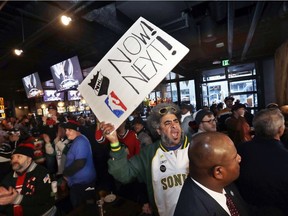 Kris "Sonic Guy" Brannon holds up a sign in support of adding an NBA team following the announcement of a new NHL hockey team in Seattle, at a celebratory party Tuesday, Dec. 4, 2018, in Seattle.