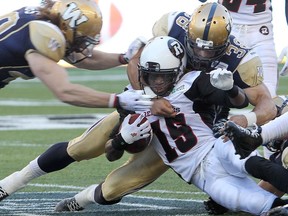 Ottawa RedBlacks wide receiver Jamill Smith (c) is hauled down by Winnipeg Blue Bombers linebackers Jesse Briggs (l) and Ian Wild during CFL football in Winnipeg, Man. Monday July 03, 2014. Brian Donogh/Winnipeg Sun/QMI Agency