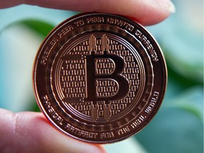 File — A person holds a Bitcoin.