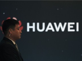 In this Jan. 9, 2019, photo, a security guard stands near the Huawei company logo during a new product launching event in Beijing.