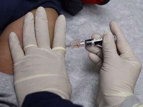 A medical assistant at the Sea Mar Community Health Center gives a patient a flu shot in Seattle on January 11, 2018. (THE CANADIAN PRESS/AP/Ted S. Warren)