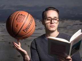 Devin Pacholik attempts to spin a basketball on his finger while reading "Women of Influence" in the Saskatchewan Arts Board building on Broad Street.