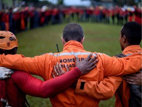 Firefighters say a prayer before resuming the search of victims 20 days after the rupture of a tailings dam of mining company Vale in Corrego do Feijao, near Brumadinho, in the Brazilian state of Minas Gerais, on February 13, 2019.