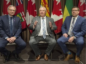 Ontario Premier Doug Ford, centre, speaks to reporters as Saskatchewan Premier Scott Moe, right, and New Brunswick Premier Blaine Higgs look on during a meeting of Canada's premiers in Montreal, Thursday, December 6, 2018.