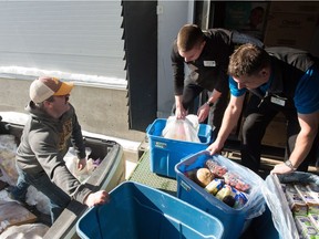 Farmer Jesse Anderson of Lajord (left) picks up totes of non-salable produce from Save On Foods in east Regina. Assistant store manager Devin Mills (centre) and store manager Rob Foster assist.