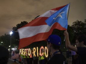 In this Sept. 20, 2018 file photo, people gather outside the White House in Washington, during a vigil commemorating the one-year anniversary of Hurricane Maria hitting Puerto Rico. A federal bankruptcy judge on Monday, Feb. 4, 2019 approved a major debt restructuring plan for Puerto Rico in the first deal of its kind for the U.S. territory since the government declared nearly three years ago that it was unable to pay its public debt.
