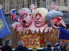 Anti-Brexit demonstrators stand next to a van with large cartoon style portraits of leading British politicians including, from right, Prime Minister Theresa May, Boris Johnson, Michael Gove, David Davis, outside the Palace of Westminster in London, Thursday, Feb. 14, 2019. British lawmakers are holding another series of votes on Brexit legislation Thursday.