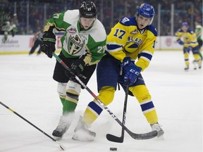 Prince Albert Raiders forward Parker Kelly fights for the puck against Saskatoon Blades forward Eric Florchuk during the game at SaskTel Centre in Saskatoon on Friday, March 15, 2019.