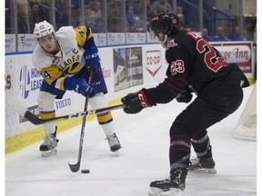 Blades forward Chase Wouters goes to move the puck past Moose Jaw Warriors forward Tristin Langan during the WHL playoffs at SaskTel Centre in Saskatoon, Sk on Saturday, March 23, 2019.