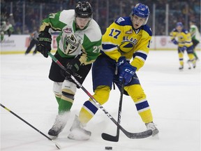 Prince Albert Raiders forward Parker Kelly fights for the puck against Blades forward Eric Florchuk during WHL action at SaskTel Centre in Saskatoon on Friday, March 15, 2019.