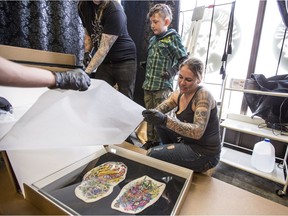 SASKATOON,SK--APRIL 12/2019-*0415 NEWS Tattoo -   Cheryl Wenzel, right, unpacks mounted pieces of tattooed skin at Electric Underground Tattoo with her son Christopher Ross Wenzel, centre and Kurt Wiscombe.  Wenzel, the wife of deceased tattoo artist Chris Wenzel, had ChrisÕs skin and his tattoos preserved through a company in the United States. ChrisÕ tattoos are set to be unveiled at the tattoo expo this weekend in Saskatoon on Friday, April 12, 2019.