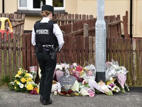 LONDONDERRY, NORTHERN IRELAND - APRIL 19: A police officer looks at flowers left in tribute to journalist Lyra McKee near the scene of her shooting on April 19, 2019 in Londonderry, Northern Ireland. Journalist and Author Lyra McKee was killed in a 'terror incident' while reporting from the scene of rioting in Derry's Creggan neighbourhood after police raided properties in the Mulroy Park and Galliagh area on the night of Thursday 18th April 2019.  Reports say that she was killed as shots were fired from a single gun. Lyra McKee was well known for covering the lasting trauma and the violence of the Northern Ireland Troubles.