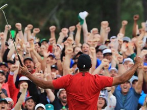 Patrons cheer as Tiger Woods of the United States celebrates after sinking his putt on the 18th green to win during the final round of the Masters at Augusta National Golf Club on April 14, 2019 in Augusta, Georgia.