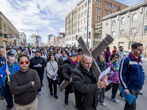 Yunan Yalbir carries a cross down Third Avenue during the 22nd annual Way of the Cross procession on Good Friday, April 19, 2019.