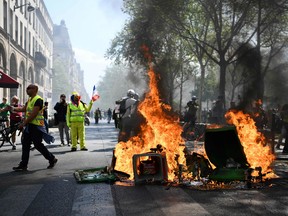 Protesters stand next to a burning barricade during an anti-government demonstration called by the "Yellow Vests" (gilets jaunes) movement, on April 20, 2019 in Paris.