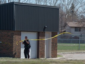 A police officer removes police tape from the perimeter of a scene of a shooting on the north side of F. W. Johnson Collegiate on Fines Drive. The incident resulted in two people being sent to hospital.