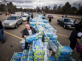 Madison Heights resident Chris Wilder, center, grabs a case of bottled water water as he works with dozens volunteers load vehicles for Flint residents on World Water Day on Friday, March 22, 2019 at Flint City Hall in Flint, Mich.. The city received 12 truckloads of bottled water, and distributed cases to residents at five different locations throughout Flint. World Water Day works as a call to action and to heighten awareness of the lack of clean water and sanitation. (Jake May/The Flint Journal via AP) ORG XMIT: MIFLI302