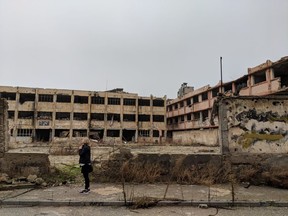 Cassandra Basnett Lee stops before a destroyed school in Homs, Syria. Her Justice Rising Organization works to support education in Aleppo and Damascus, Syria.