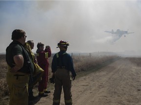 Fire crews watch a water plane spray over to control a wildfire near Biggar, Sask., on Tuesday, April 23, 2019.