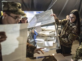 Ukrainian government soldiers, members of the local election commission, open a ballot box in a tent using as a polling station during the president elections in Mariinka, near a contact line not far from Donetsk, eastern Ukraine, Sunday, March 31, 2019.