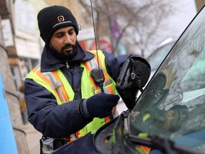 A parking enforcement official prints out a ticket for a vehicle parked downtown in Saskatoon on April 26, 2017.