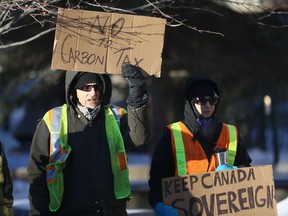 Kane Milani and Tera Nicholson protest outside City Hall on Saturday, Dec. 8, 2018, as part of a group of "yellow vest" protestors rallying against the carbon tax and the federal government's decision to sign on to the UN's global migration compact.