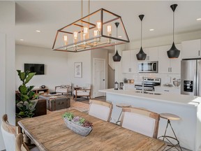 Arbutus Properties' design team selected a Scandinavian 'hygge' theme for the interior of its new Clarke show home. Black matte designer lighting fixtures and hardware stand out against the kitchen's crisp white cabinets and quartz counters. Rustic woodgrain wide plank laminate flooring brings warmth to the great room.