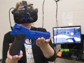 Megan Smith, associate professor in the Faculty of Media, Art, and Performance at the University of Regina, shows a VR-compatible remote control she made that looks and feels like a real weapon for RCMP simulation training.