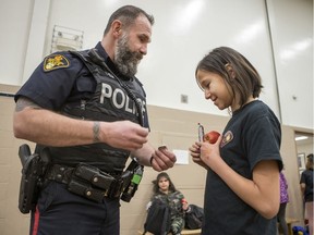 Peacekeeper cadet Rayne Charles shows a button to Saskatoon police Const. Derek Chesney at Princess Alexandra Community School