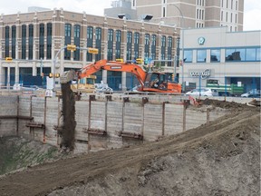 A track hoe pours dirt into the Capital Pointe hole.