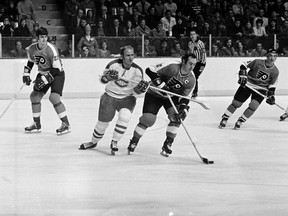 Ed Van Impe #2 of the Philadelphia Flyers skates past Jacques Lemaire #25 of the Montreal Canadiens with the puck circa 1972 at the Montreal Forum in Montreal, Que.