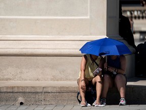 People use an umbrella to shelter from the sun near the Louvre Pyramid (Pyramide du Louvre) during a heatwave in Paris on June 26, 2019. - Forecasters say Europeans will feel sizzling heat this week with temperatures soaring as high as 40 degrees Celsius (104 degrees Fahrenheit) in an "unprecedented" June heatwave hitting much of Western Europe.