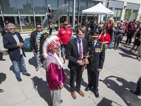 Saskatoon Tribal Council Chief Felix Thomas, left, presents a gift to Saskatoon Mayor Charlie Clark as Saskatoon police Chief Clive Weighill, right, looks on following an event unveiling of a missing and murdered indigenous women monument at the entrance to the Saskatoon Police headquarters a  in Saskatoon, SK on Friday, May 5, 2017.