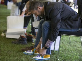 Yukon Premier Sandy Silver puts on a pair of moccasins that he received as a gift during a community event and gift giving ceremony in Big River on July 9, 2019.