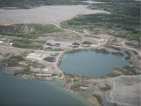 An aerial view of the abandoned Gunnar mine site near Uranium City, Sask. The flooded mine pit is in the centre, above the waste rock pile and below one of three tailings deposits on the site. Piles of demolition debris surround the pit.