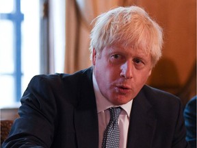 Britain's Prime Minister Boris Johnson (L) speaks flanked by Youth Justice Board Adviser Roy Sefa-Attakora (R) during a roundtable on the criminal justice system at 10 Downing Street in London on August 12, 2019.