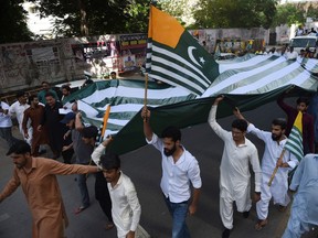Pakistanis hold a giant flag of Pakistan-administered Kashmir during an anti-Indian protest in Karachi on August 18, 2019. - Tensions have soared since India earlier this month stripped the part of Kashmir that it controls of its autonomy, sparking calls from Pakistan for the international community to intervene on the decades-old issue.
