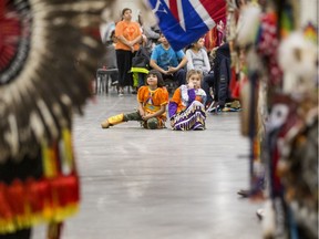 Two young dancers watch the Grand Entry at the Welcome Back Wacipi Pow Wow hosted by Saskatoon Public Schools at Prairieland Park.
