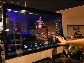 Maggie Lu is reflected in a touch screen as she demonstrates how to select a class on a Peloton Tread treadmill during CES 2018 at the Las Vegas Convention Center on January 11, 2018 in Las Vegas, Nevada.