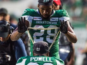 Saskatchewan Roughriders defensive back Loucheiz Purifoy drapes the team's Big Play Chain around the neck of running back William Powell. Greater rewards will be forthcoming if the Roughriders can win the race for first place.