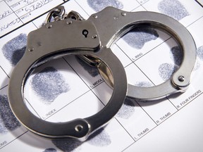 In this stock photo, handcuffs lay on top of a fingerprint chart.