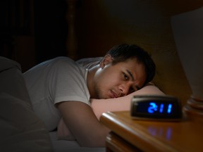 Depressed man suffering from insomnia lying in bed