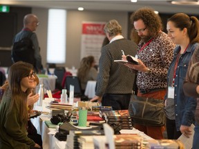 People browse a table with books for sale during a Saskatchewan Writers' Guild event being held at the Travelodge hotel on Albert Street.