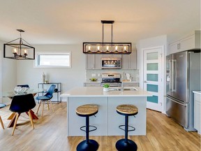 Warman Homes designed its latest show home for modern family living, located at 812 First Avenue North in Warman. The welcoming kitchen, crafted by Warman Cabinets, features V-groove Shaker-style cabinets, complemented by a grey glass tile backsplash and white quartz counters. Photo: Scott Prokop Photography