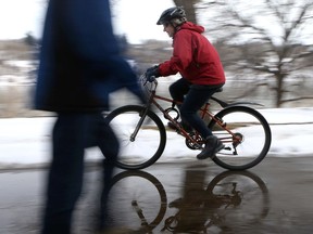 A cyclist rides through puddles on the Meewasin Trail in Saskatoon on March 15, 2017. Saskatoon city council endorsed a number of changes to cycling rules on Nov 18, 2019, including a proposed one-metre buffer for cyclists passing pedestrians.