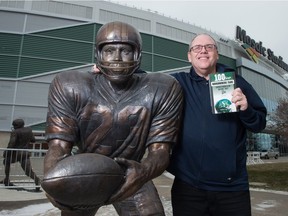 Veteran Leader-Post sports columnist Rob Vanstone stands with the statue of Ron Lancaster at Mosaic Stadium while holding a copy of his new book about the Saskatchewan Roughriders. BRANDON HARDER/ Regina Leader-Post