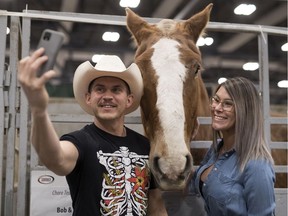 Curtus Collins and his fiancé Michelle Blaser take a selfie with a chore horse from the barns of Wayne Nagy-Diamond Horseshoe Ranch, of Melville, Sask., during the Canadian Western Agribition in Regina.
