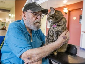 Warren McKay strokes Tig, a cat who lives at Sherbrooke Community Centre. The consistent but controlled presence of animals is part of what makes the long-term care home in Saskatoon unique.