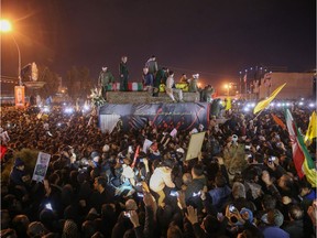Iranians gather around a vehicle carrying the caskets of slain military commander Qasem Soleimani and others during a funeral procession in the Iranian city of Qom on Jan. 6, 2020.